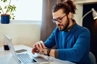 person looking at their watch while working at a laptop