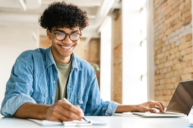 person working on their laptop and taking notes