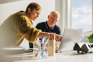 two people discussing work on a laptop