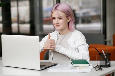 person doing a thumbs up while working at their laptop