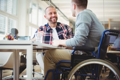 a disabled man at work talking to a colleague