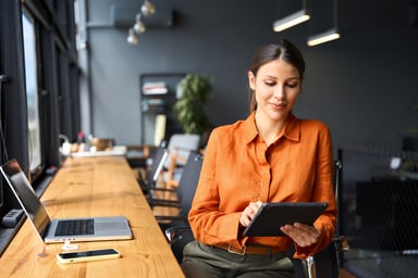 Person in orange shirt using a tablet.