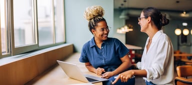 Two people sat in front of a laptop, smiling and talking